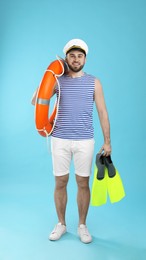 Photo of Sailor with ring buoy and swim fins on light blue background