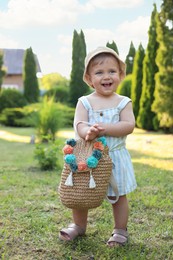 Cute little girl in stylish clothes with knitted backpack outdoors on sunny day