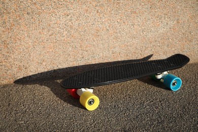 Black skateboard with colorful wheels on asphalt outdoors