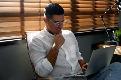 Freelancer working on laptop near window indoors