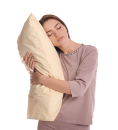 Young woman wearing pajamas with pillow in sleepwalking state on white background