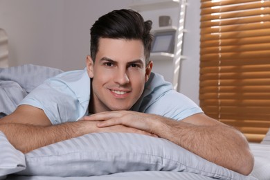 Man lying in comfortable bed with light grey striped linens