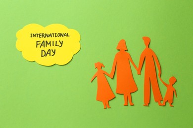 Paper cutout and card with text International family day on light green background, flat lay