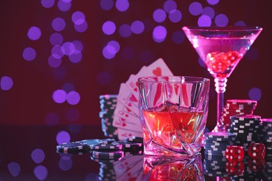 Alcohol drinks, dice, playing cards and casino chips on table against blurred lights, space for text. Straight poker combination