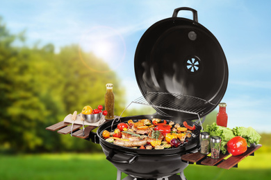 Image of Barbecue grill with meat products and vegetables outdoors on sunny day