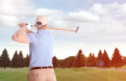 Young man playing golf on course with green grass, back view. Space for design