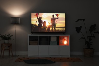 Modern TV set on wooden stand in room