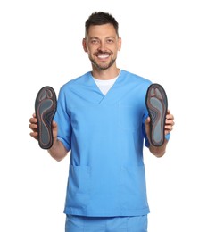 Handsome male orthopedist showing insoles on white background