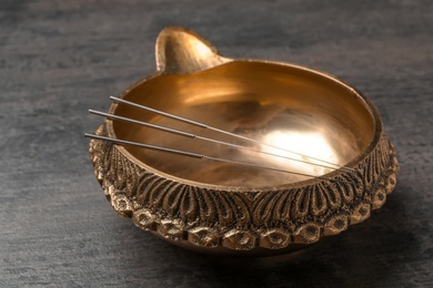 Golden bowl with needles for acupuncture on table