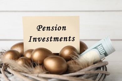 Many golden eggs, money and card with phrase Pension Investments against white wooden wall