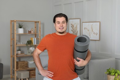 Overweight man with yoga mat at home