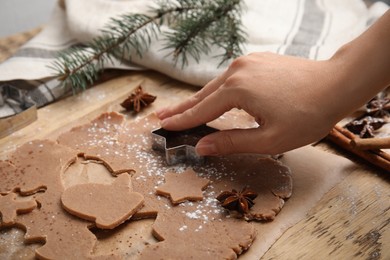 Woman making gingerbread Christmas cookies at wooden table, closeup