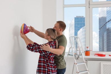Photo of Couple with paint chips discussing new wall color in apartment during repair