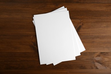 Stack of blank paper sheets on wooden table, top view. Brochure design