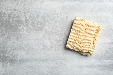 Photo of Block of quick cooking noodles on color background, top view. Space for text
