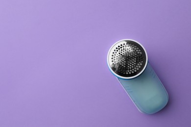 Modern fabric shaver to remove lint on purple background, top view. Space for text