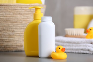 Photo of Baby cosmetic products and rubber duck on grey table