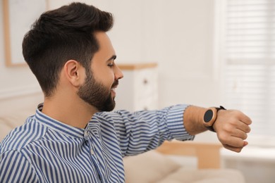 Young man looking at smart watch in apartment