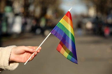 Woman holding bright LGBT flag on city street, closeup