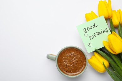 Cup of aromatic coffee, beautiful yellow tulips and Good Morning note on white background, flat lay. Space for text