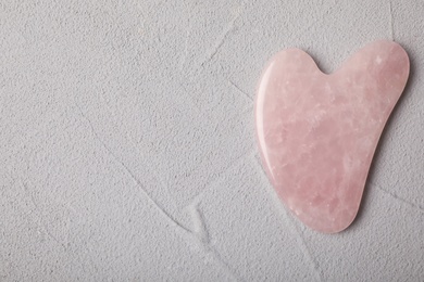 Photo of Rose quartz gua sha tool on grey table, top view. Space for text