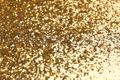 Photo of Shiny bright golden glitter as background, closeup