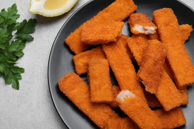 Fresh breaded fish fingers served on light grey table, flat lay