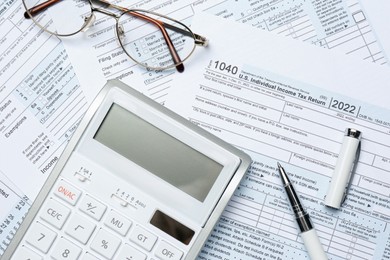 Calculator, glasses and pen on documents, flat lay. Tax accounting