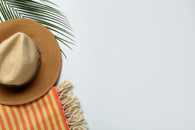 Beach towel and straw hat on light background, flat lay. Space for text