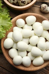 Photo of Unpeeled and peeled boiled quail eggs on wooden table, flat lay