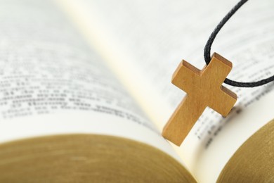Christian cross on open Bible, closeup view