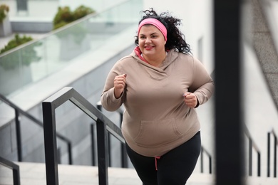 Beautiful overweight woman running up stairs outdoors