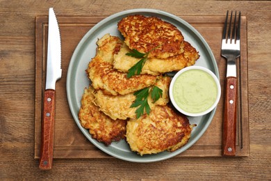 Photo of Tasty parsnip cutlets with parsley and sauce served on wooden table, top view