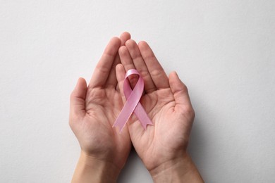 Woman holding pink ribbon on white background, top view. Breast cancer awareness concept