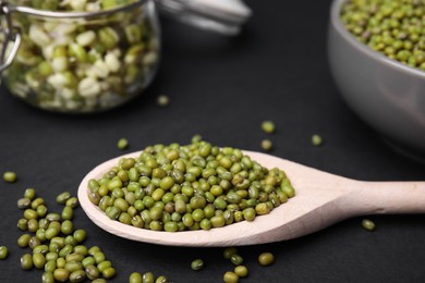 Different dishware with green mung beans on black background, closeup