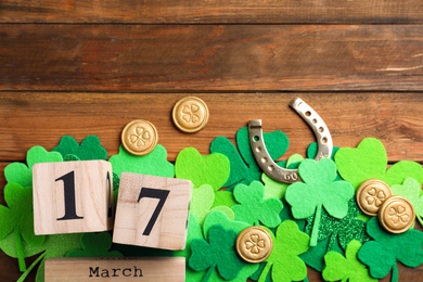 Flat lay composition with horseshoe and block calendar on wooden background, space for text. St. Patrick's Day celebration