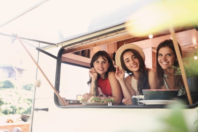 Happy young women in trailer, view from outside. Camping vacation