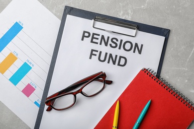 Stationery, glasses, notebook, chart and paper with words PENSION FUND on table, flat lay
