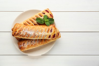 Photo of Fresh tasty puff pastry with sugar powder and mint on white wooden table, top view. Space for text
