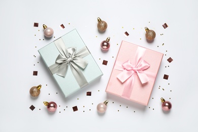 Photo of Beautiful gift boxes, Christmas balls and confetti on white background, flat lay