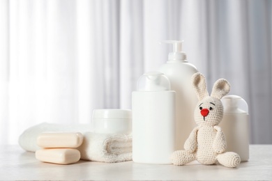 Baby cosmetic products, toy and towel on table indoors