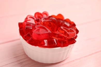 Tasty heart shaped jelly candies on pink table
