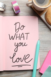 Photo of Open notebook with motivational phrase Do What You Love on wooden table, flat lay