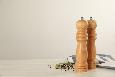 Wooden salt and pepper shakers with napkin on table against white background, space for text. Spice mill