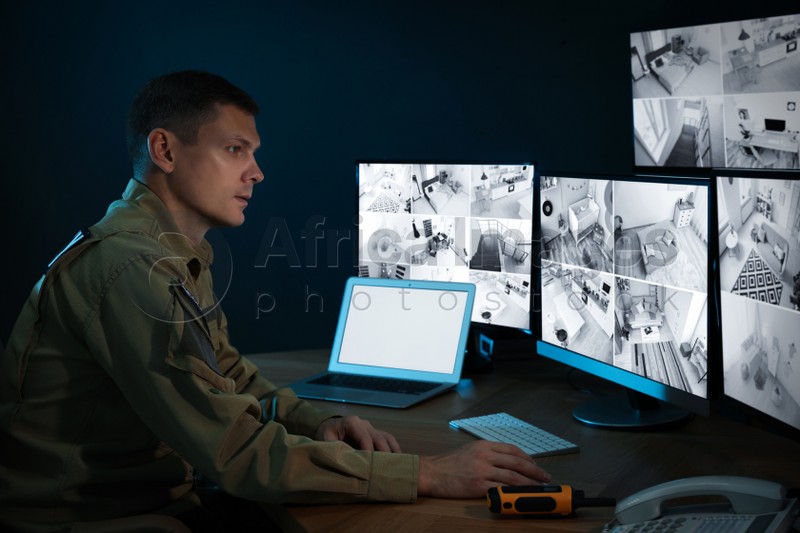 Photo of Security guard monitoring modern CCTV cameras in office