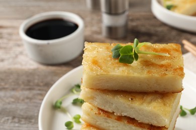 Delicious turnip cake with microgreens served on wooden table, closeup