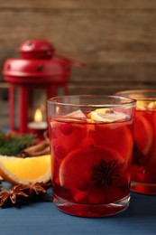 Delicious punch drink with cranberries and orange on blue wooden table