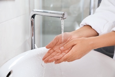 Woman washing hands over sink in bathroom, closeup. Using soap