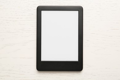 Modern e-book reader with blank screen on white wooden table, top view