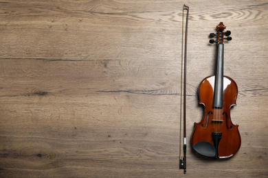 Classic violin and bow on wooden background, flat lay. Space for text